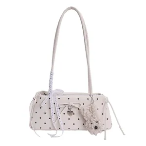 Polka dot baguette bag with lace bow and puppy plush keychain on white background