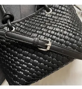 Dettaglio della borsa tote nera intrecciata con tracolla regolabile e fibbia in metallo