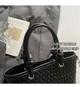 Dettaglio della borsa tote nera intrecciata con manico cilindrico e nodi decorativi