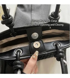 Dettaglio della borsa a secchiello nera intrecciata con chiusura magnetica in argento