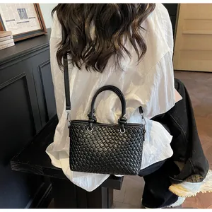 Dettaglio borsa tote intrecciata nera con motivo a scacchi e manico cilindrico in pelle