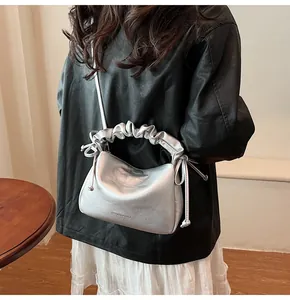 Detailansicht der silbernen Plissee-Handtasche mit Metallic-Finish und Schriftzug