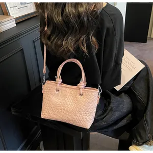 Dettaglio della borsa tote rosa intrecciata con manici annodati e finitura in pelle a trama