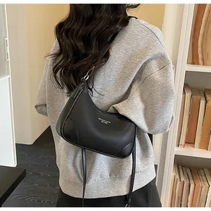 Rear view of model wearing a black pebbled leather hobo bag with silver letter logo