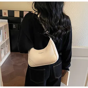 Detail of a creamy white hobo bag with pebble leather texture and metal buckle on strap