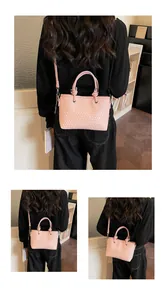 Dettaglio della borsa tote rosa intrecciata con manici cilindrici e anelli metallici argento