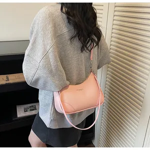 Detail of light pink lychee pattern leather shoulder bag with sleek brand logo text