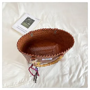 Top view of woven tote bag featuring bamboo handles and colorful decorative tassel charm