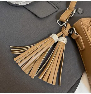Gros plan du sac seau en cuir beige avec double gland et anneaux en strass étincelants