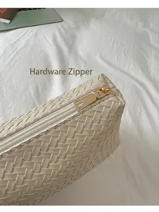 Dettaglio della cerniera in metallo dorato su borsa in pelle intrecciata beige