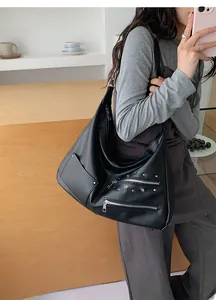 Close-up of black Hobo shoulder bag with silver studs and decorative side zippers