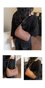 Close-up of brown pebbled leather crescent bag with silver metallic zipper and brand logo