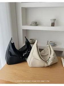Detail of hobo shoulder bags in black and beige with vintage zippers and metal rivets