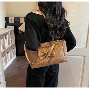 Close-up of woven brown tote bag featuring a decorative bow and metal buckle clasp