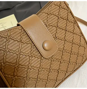 Détail de la texture géométrique ondulée et du fermoir d'un sac seau en cuir marron