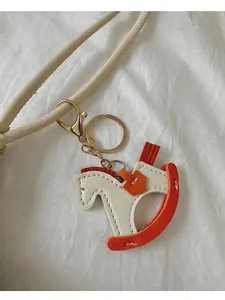 Dettaglio del ciondolo a cavallo in pelle bicolore con cuciture e chiusura in metallo oro