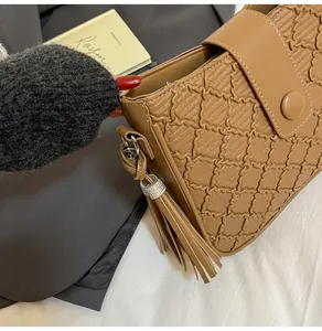 Détail du sac seau marron caramel matelassé avec pompon et coutures ondulées