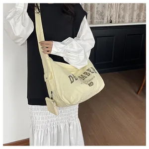 Detail einer beigefarbenen Nylontasche mit kleinem abnehmbarem Beutel und Stickerei