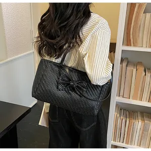 Detail of black woven tote bag featuring a large bow and soft textured finish