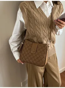 Vue détaillée du sac seau marron avec texture à losanges et breloque à pompon chic