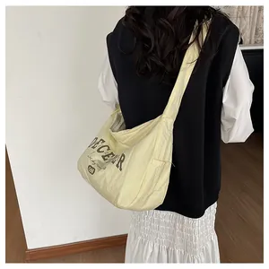 Detail einer hellgelben Nylon-Umhängetasche mit lässigem Buchstabendruck auf der Schulter