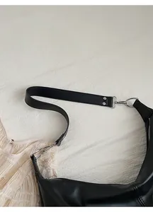 Detail of a wide black leather shoulder strap with silver rivets on a vintage tote bag