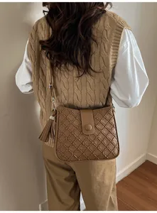 Sac seau marron avec texture tressée et pompon porté par un mannequin de dos