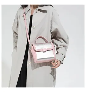 Detail of pink leather handbag with silver metallic flap on a beige trench coat