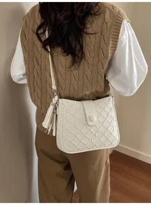 Détail du sac seau blanc avec gaufrage géométrique texturé et accessoire à franges