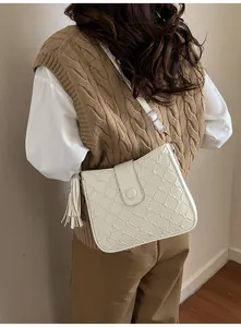 Détail du sac seau blanc avec texture tissée et breloque à pompon élégante