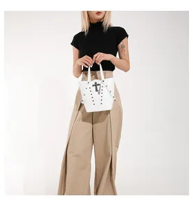 Detail of white bucket bag with gothic black cross relief and rivets on leather