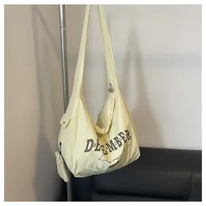 Detail der cremefarbenen Nylontasche mit December-Aufdruck und abnehmbarer Münzbörse