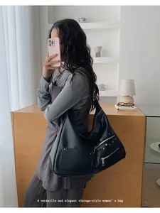 Close-up of black retro tote bag with multiple zip pockets and rivet details in daily use