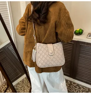 Détail macro du sac seau matelassé beige avec fermoir rond et pompon décoratif élégant