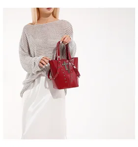 Close-up of red leather bucket bag featuring metal cross and gothic punk stud details