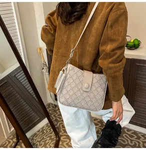 Sac seau beige avec matelassage en losanges et pompon porté en scène décontractée