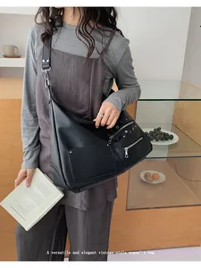 Close-up of black retro hobo bag featuring silver zippers and metallic stud details