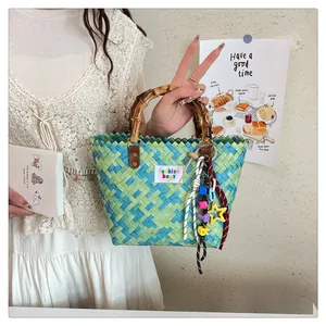 Detail of hand-woven green and blue tote with bamboo handles and colorful star charms