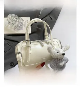 Detail of cream white cylinder bag with cute teddy bear charm and adjustable strap