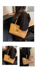 Detail of camel woven tote bag featuring a large decorative bow and metallic buckle