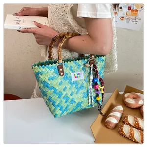 Detail of blue-green woven bag featuring natural bamboo handle and leather attachments