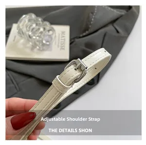 Close-up of adjustable cream leather shoulder strap with polished silver metal buckle