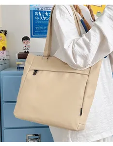 Detail of beige canvas tote bag showing side bottle pocket and minimalist woven label