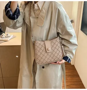 Détail du sac seau matelassé beige montrant la texture du cuir PU et le pompon décoratif
