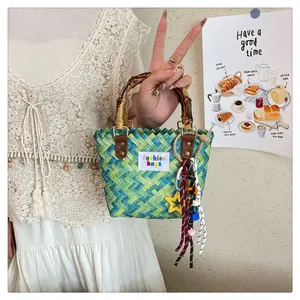 Detail of woven straw handbag featuring bamboo handle and colorful star pendants