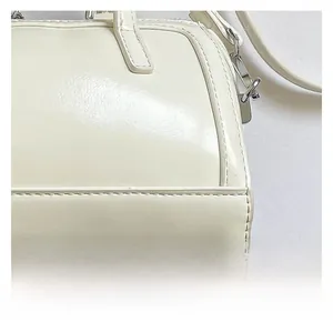 Detail shot of the cream cylindrical bag showing neat stitching and silver metal D-rings