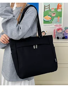 Detail of black canvas tote bag featuring double front zipper pockets and side woven label