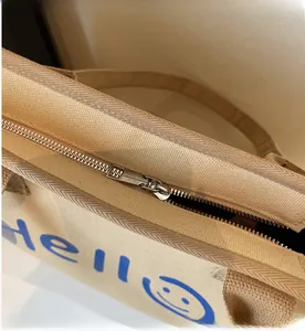 Detail of smooth metal zipper and blue Hello print on beige canvas tote bag
