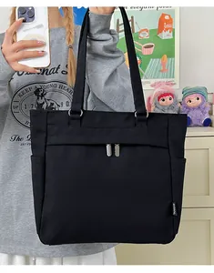 Detail of black canvas tote bag featuring front zipper pockets and side slip compartment