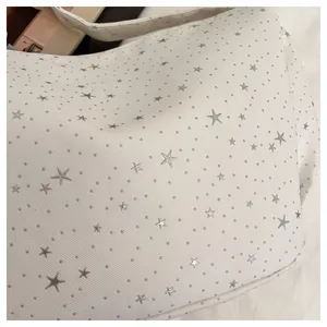 Detailed macro view of cream canvas fabric featuring silver star patterns and dots texture
